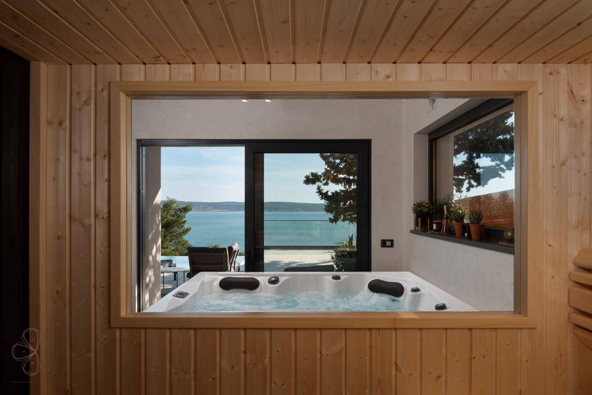 Entspannender Wellnessbereich mit Whirlpool und großem Fenster, das einen Blick auf das Meer freigibt.