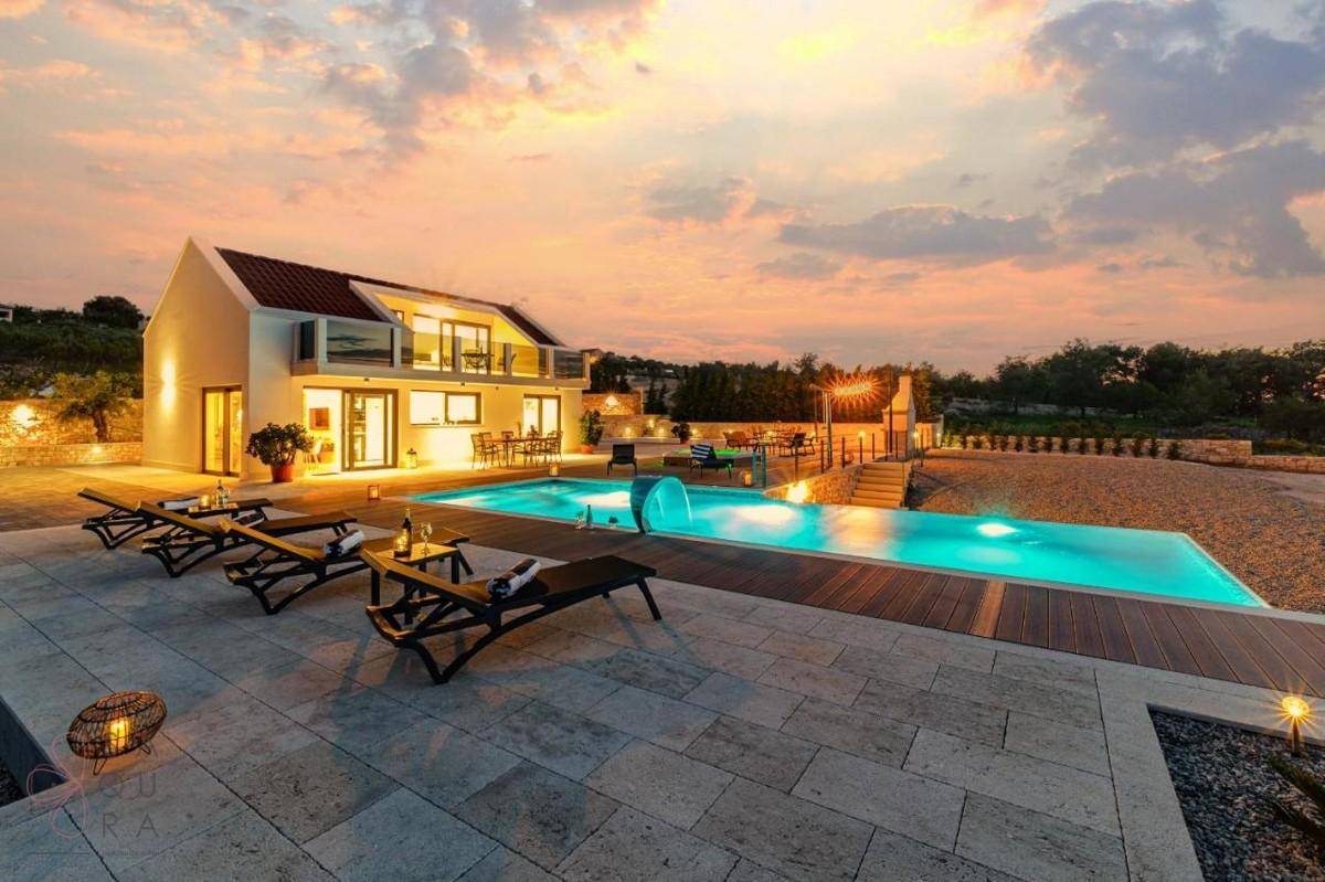 Elegante Villa mit Pool und Whirlpool bei Sonnenuntergang, umgeben von mediterraner Landschaft.