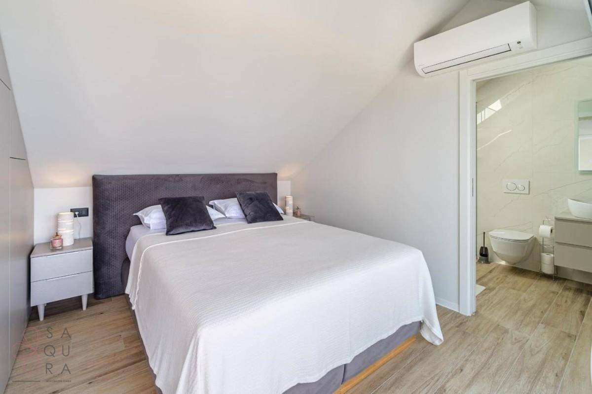 Gemütliches Schlafzimmer mit Doppelbett, Dachschräge und direktem Zugang zum Badezimmer.