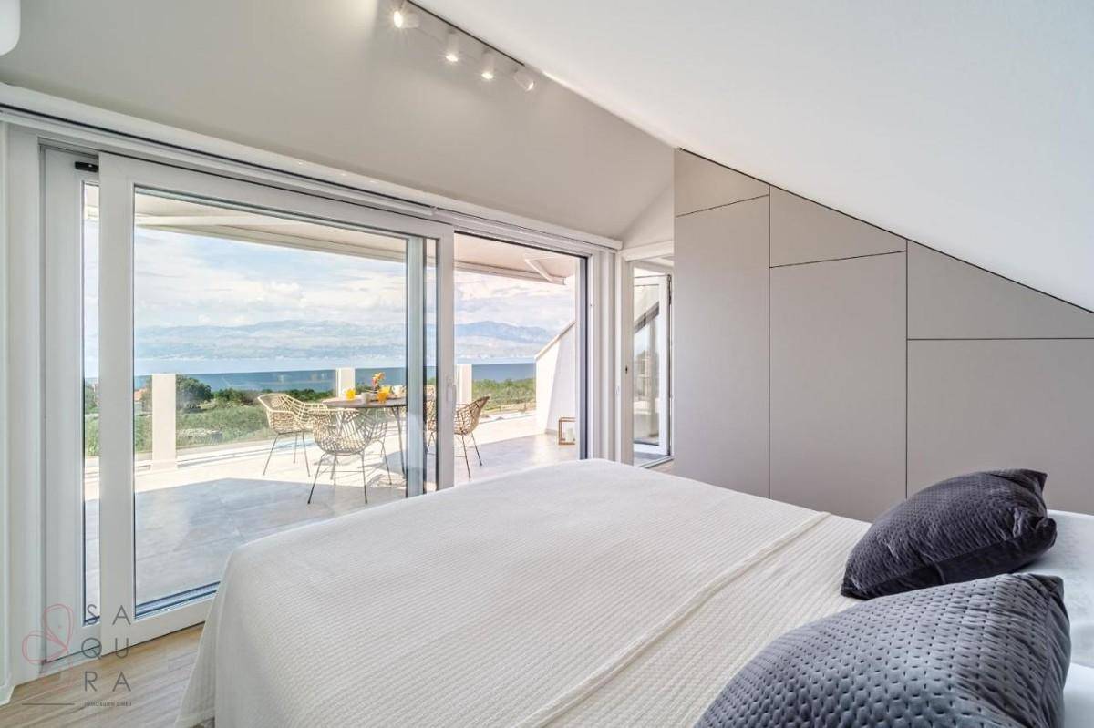 Helles Schlafzimmer mit großen Glasschiebetüren, die zu einer Terrasse mit Meerblick führen.