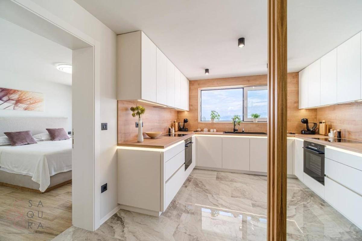 Moderne Küche mit Blick in ein Schlafzimmer, ausgestattet mit weißen Schränken und Holzdetails.