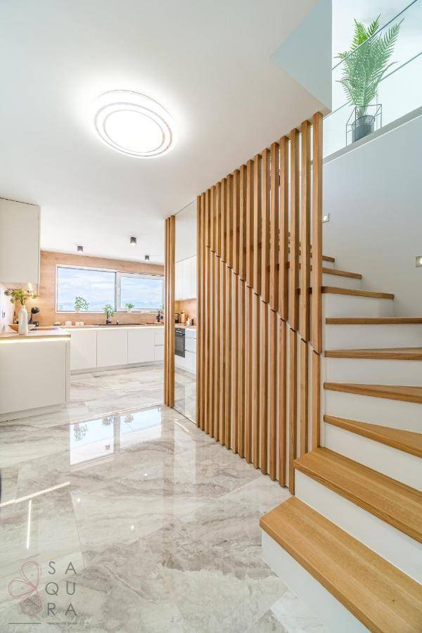 Heller Flur mit moderner Holzlamellenwand und Treppe, die zu den oberen Etagen führt.