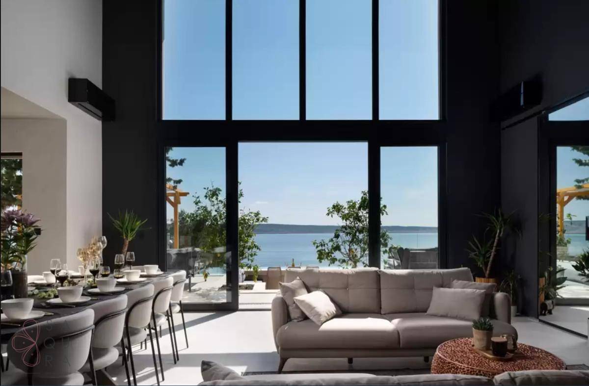 Heller Wohn- und Essbereich mit hohen Decken und Panoramafenstern, die einen weiten Meerblick bieten.