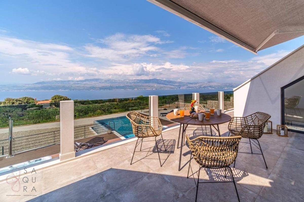 Obere Terrasse mit Esstisch, Korbstühlen und Panoramablick auf das Meer und die umliegende Landschaft.