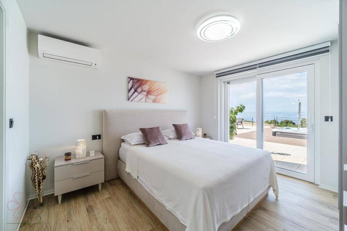 Helles Schlafzimmer mit Doppelbett, Holzboden, Klimaanlage und Zugang zur Terrasse.