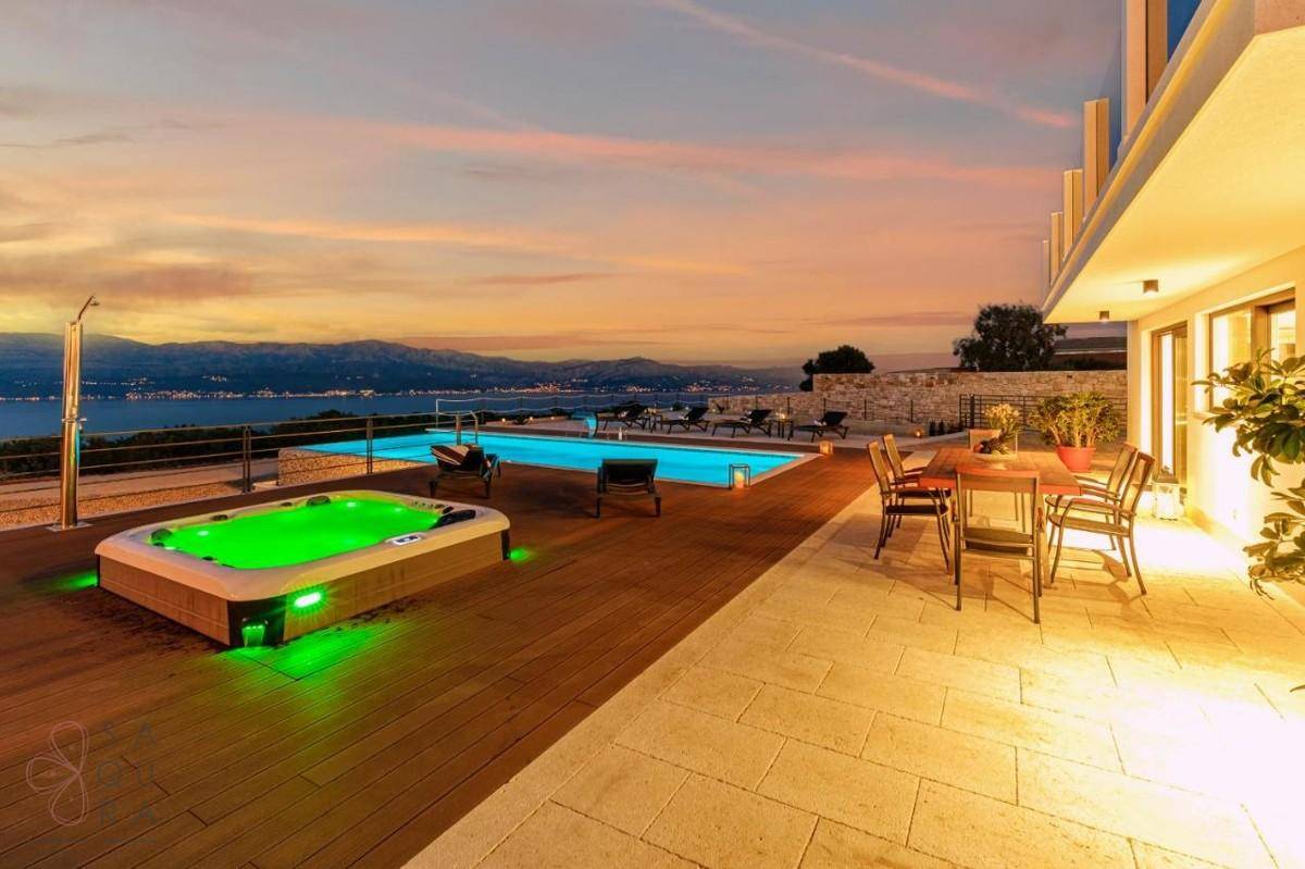 Geräumige Terrasse mit Whirlpool, Essbereich und atemberaubendem Meerblick bei Sonnenuntergang.