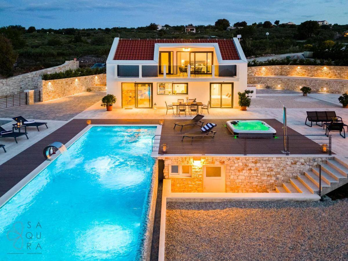 Luxuriöse Villa mit großem Pool, Whirlpool und Steinfassaden bei Dämmerung.