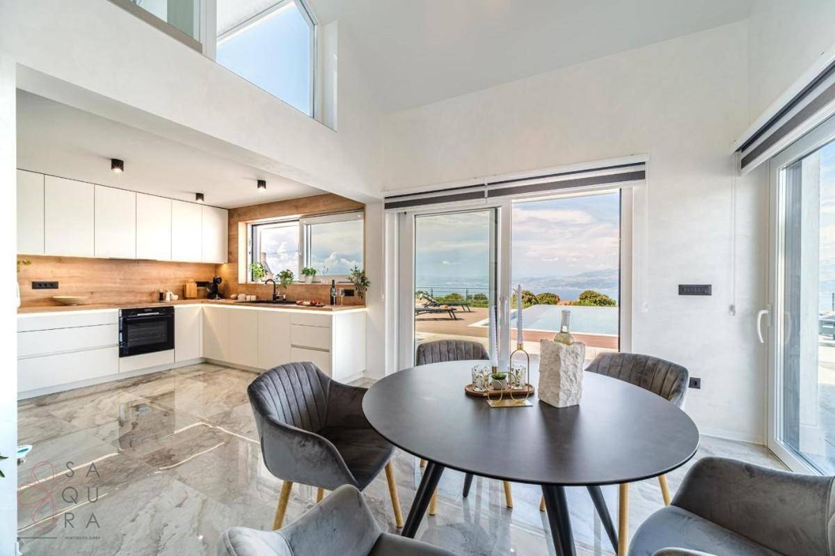 Moderne Küche mit Essbereich, großen Schiebetüren und Panoramablick auf das Meer.