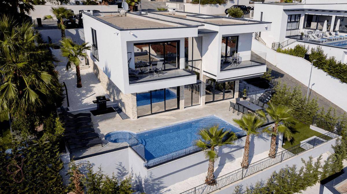Moderne Villa mit Infinity-Pool, Palmen und großzügigen Terrassenbereichen.