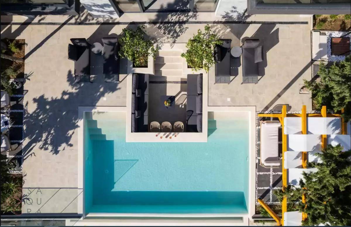 Vogelperspektive des luxuriösen Poolbereichs mit Lounge-Möbeln und Pergola.