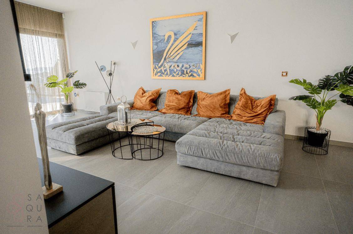 Modern eingerichtetes Wohnzimmer mit großem Sofa, Kunstwerk und Pflanzen.