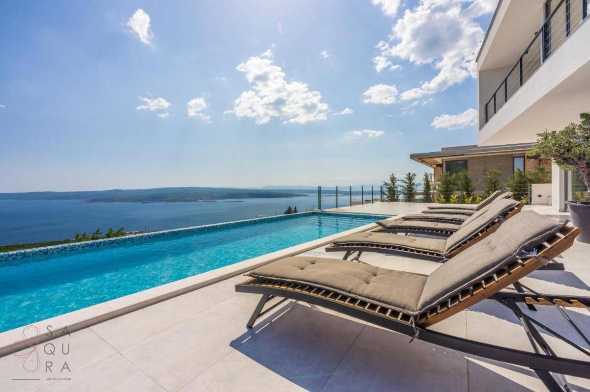 Luxuriöser Poolbereich mit Meerblick und Sonnenliegen, perfekt für entspannte Stunden im Freien.