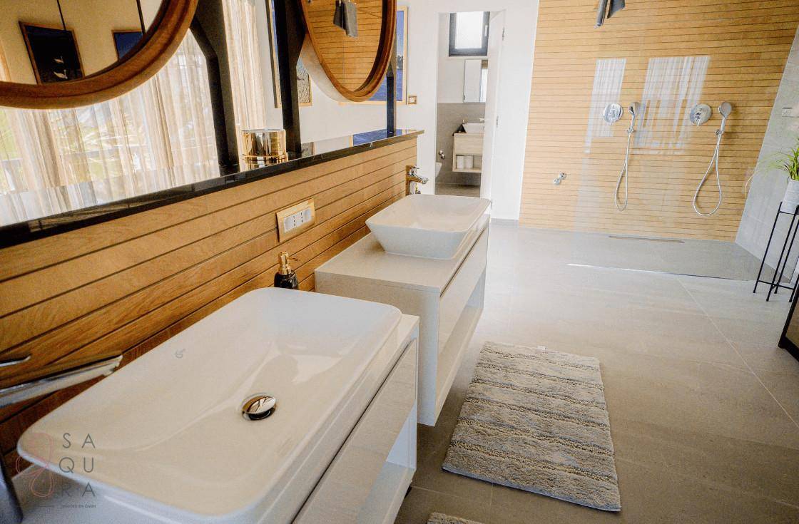 Geräumiges Badezimmer mit Doppelwaschbecken, Holzvertäfelung und begehbarer Dusche.