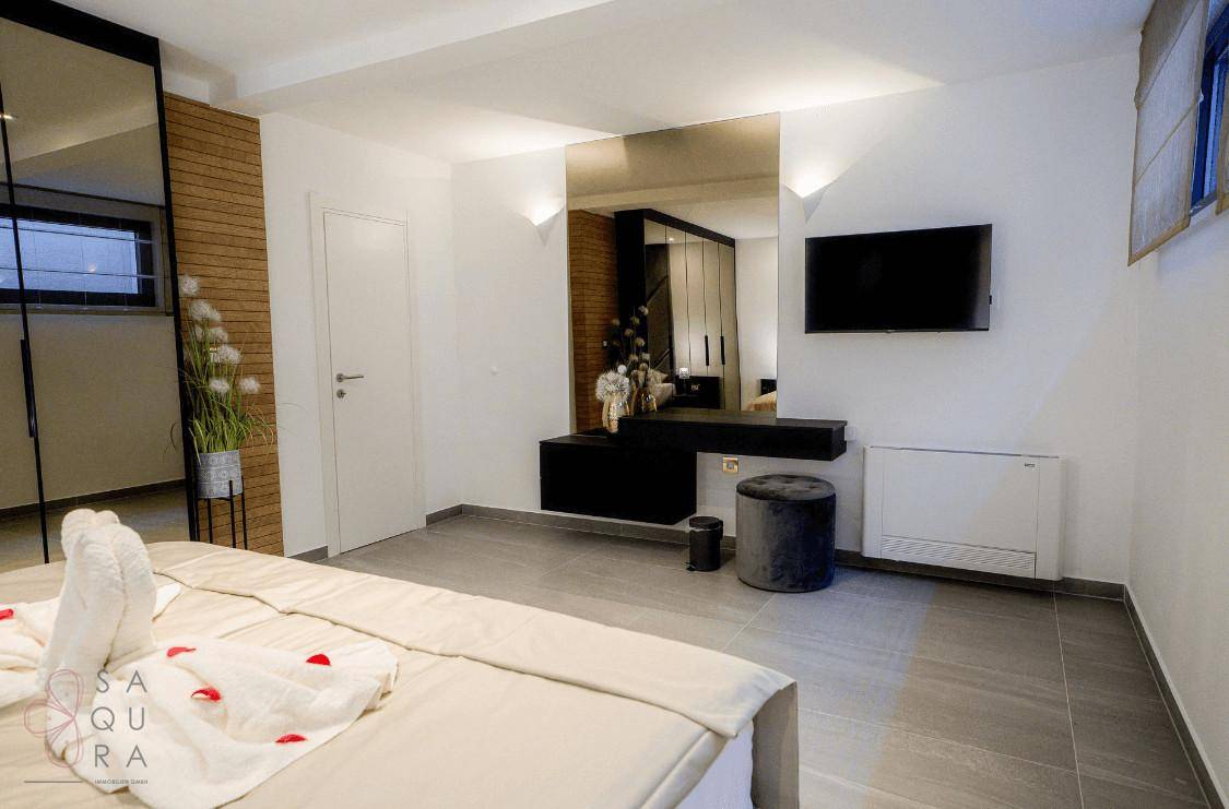 Geräumiges Schlafzimmer mit Schminktisch, Fernseher und stilvoller Einrichtung.