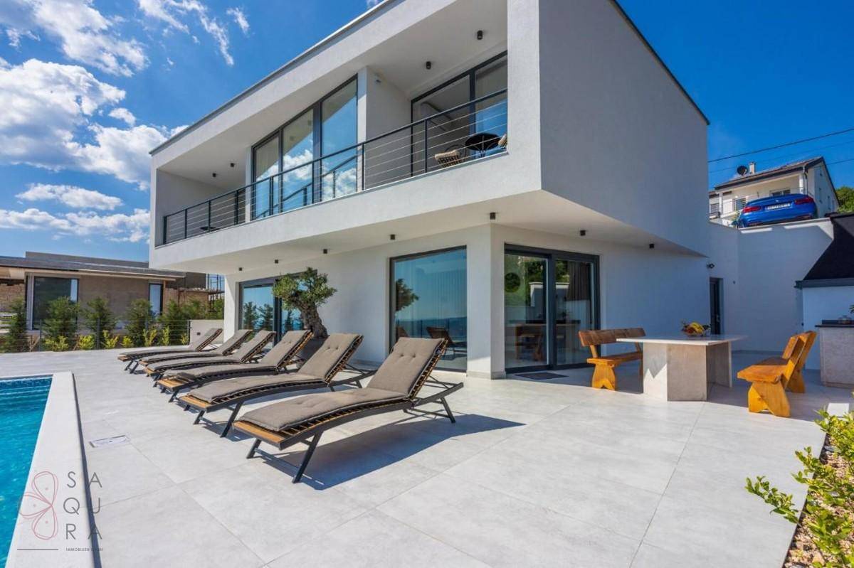 Weitläufiger Außenbereich einer modernen Villa mit Pool, Sonnenliegen und Essbereich im Freien.