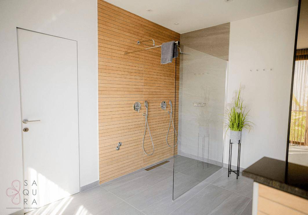 Große begehbare Dusche mit zwei Duschköpfen und stilvoller Holzvertäfelung.