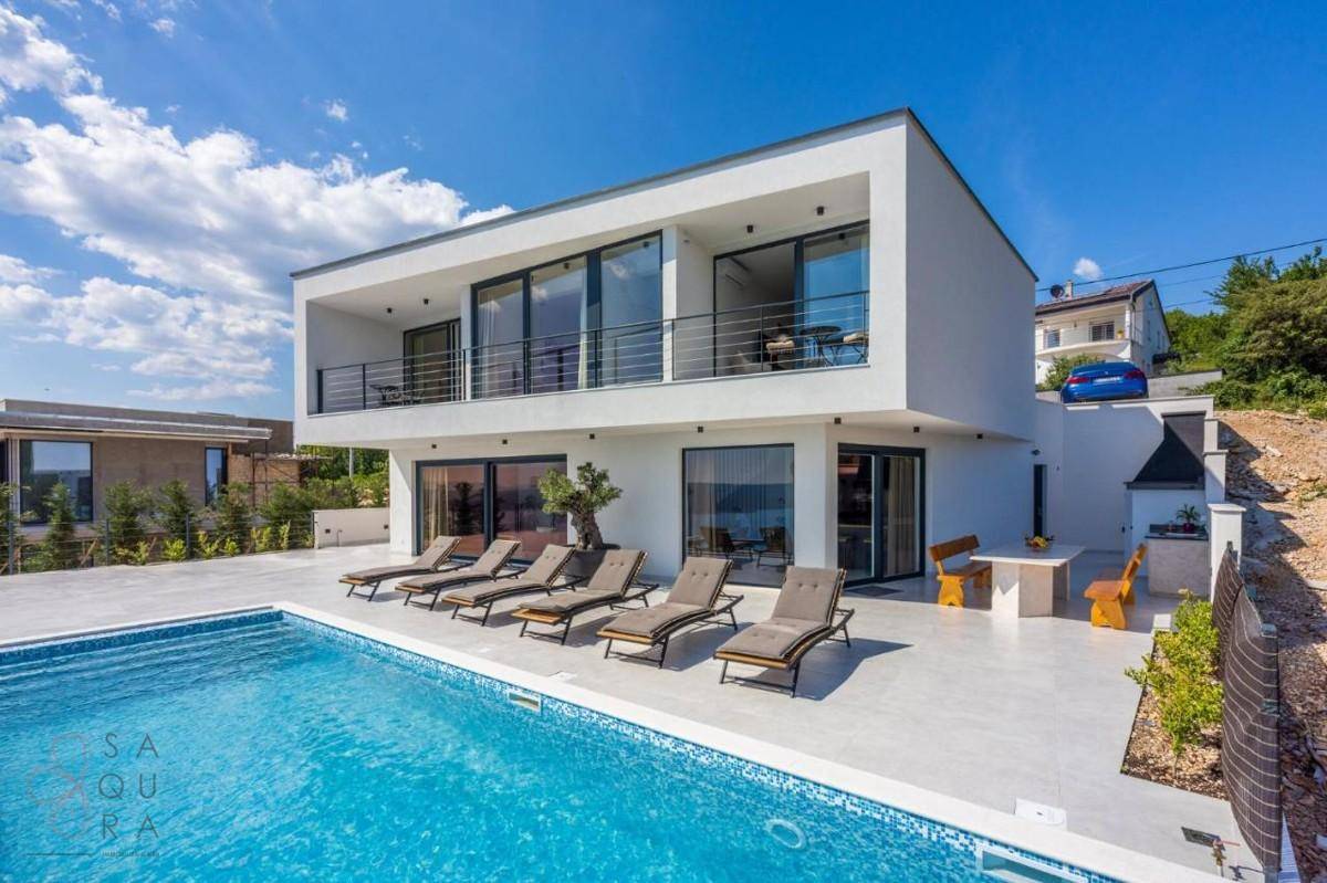 Weitläufiger Außenbereich einer modernen Villa mit Pool, Sonnenliegen und Essbereich im Freien.