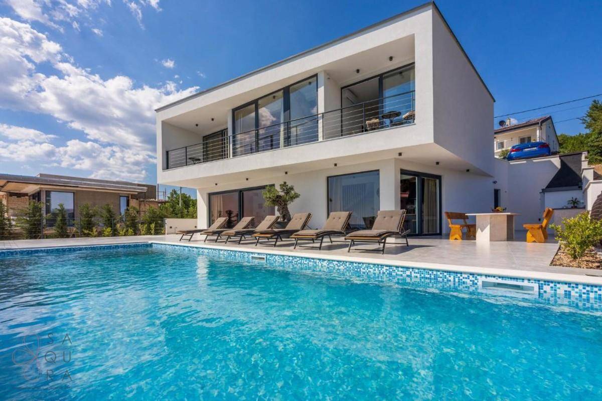 Luxuriöse Villa mit großem Pool und weitläufiger Terrasse, ideal für Entspannung unter blauem Himmel.