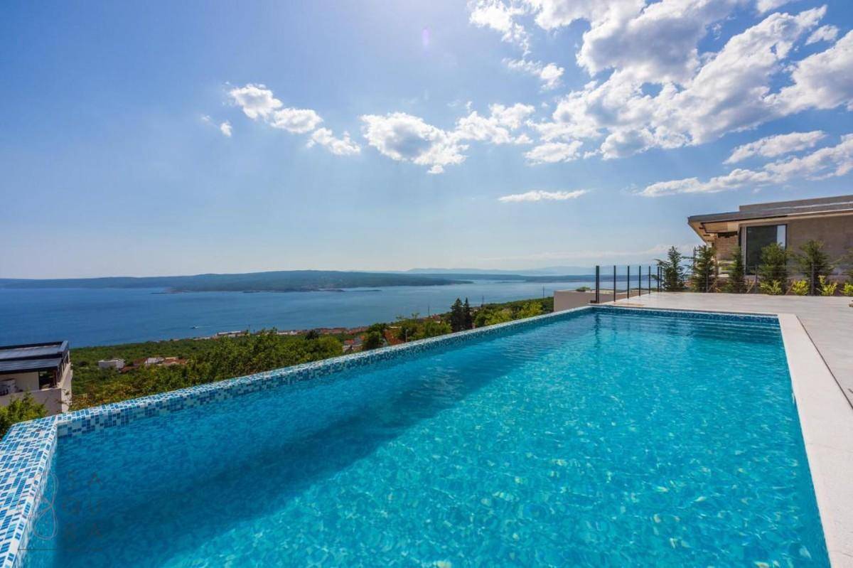 Infinity-Pool mit atemberaubendem Meerblick und bequemen Sonnenliegen auf der Terrasse.