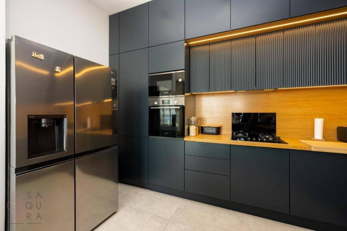 Hochmoderne Küche mit großem Kühlschrank, integrierten Backöfen und Gasherd auf Holzarbeitsplatte.