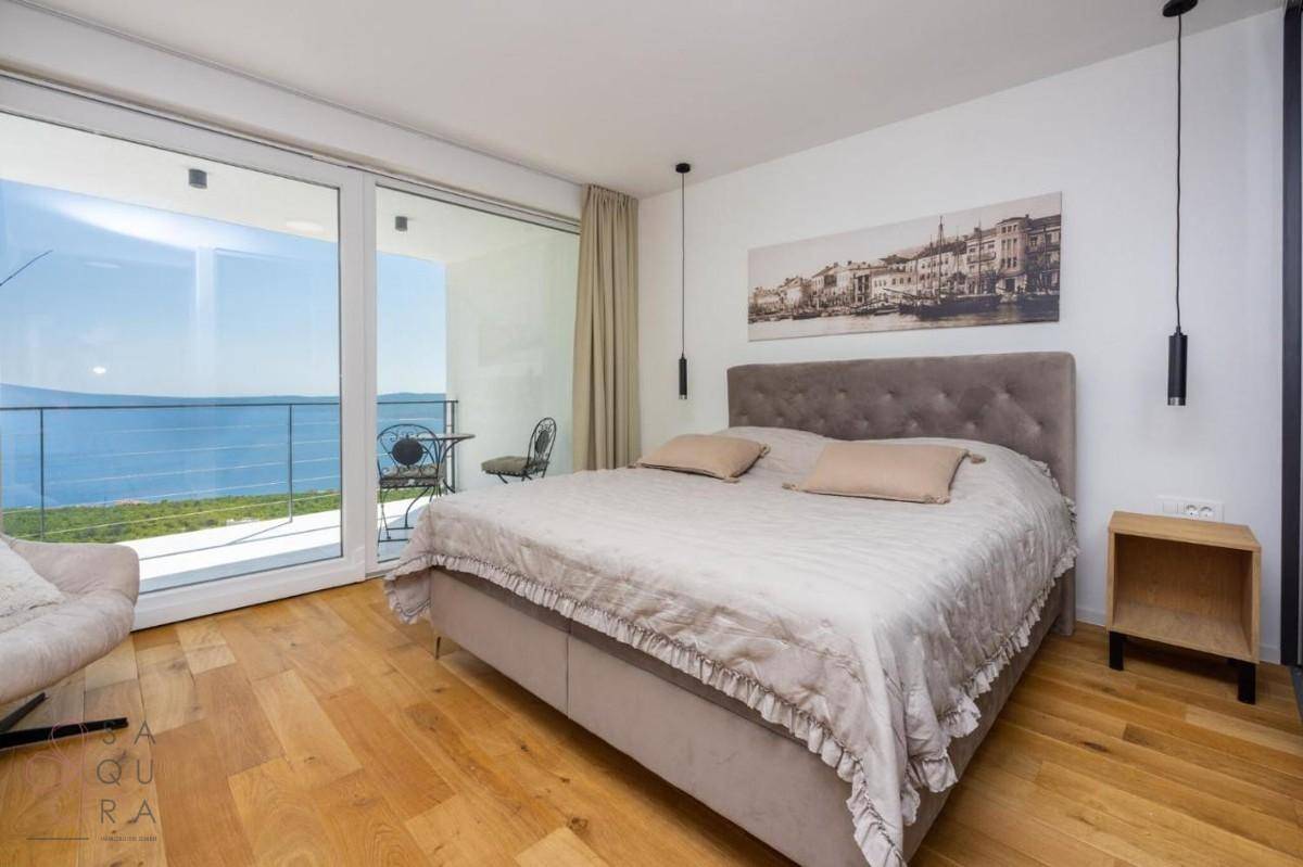 Komfortables Schlafzimmer mit Doppelbett, Nachttischen und weitem Meerblick durch die großen Fenster.