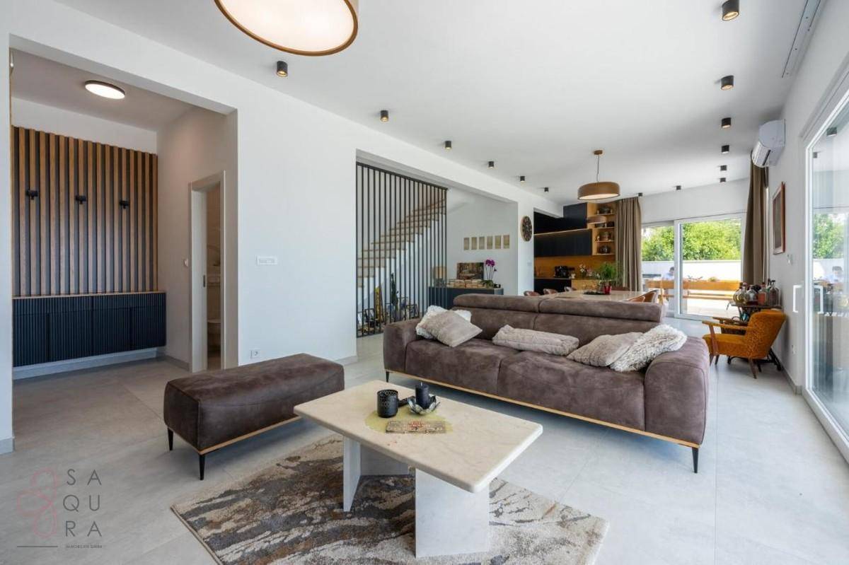Heller, offener Wohnbereich mit moderner Einrichtung, bequemer Couch und Zugang zur Treppe.