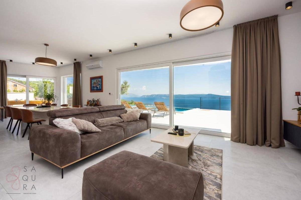 Offener Wohn- und Essbereich mit Meerblick, bequemer Couch und großem Esstisch.