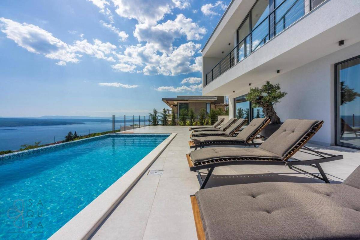 Luxuriöser Poolbereich mit Meerblick und Sonnenliegen, perfekt für entspannte Stunden im Freien.