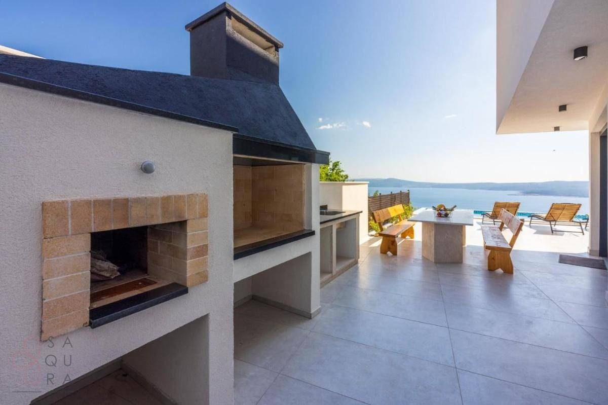 Gemütlicher Essbereich im Freien mit Grill und Meerblick, perfekt für gesellige Runden.
