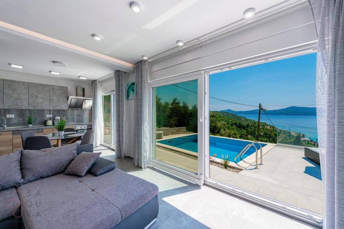 Helles Wohnzimmer mit großen Schiebetüren, die zum Poolbereich und Meerblick führen.