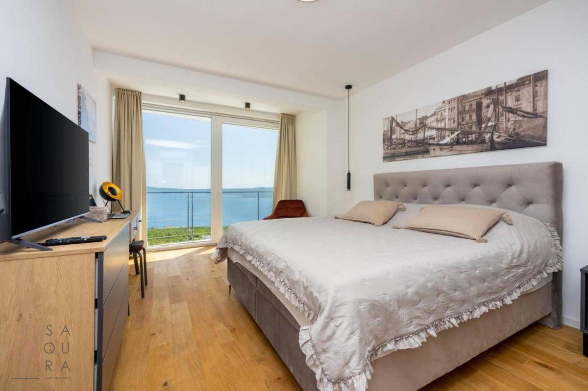Geräumiges Schlafzimmer mit großem Bett, Fernseher und raumhohen Fenstern mit herrlichem Meerblick.