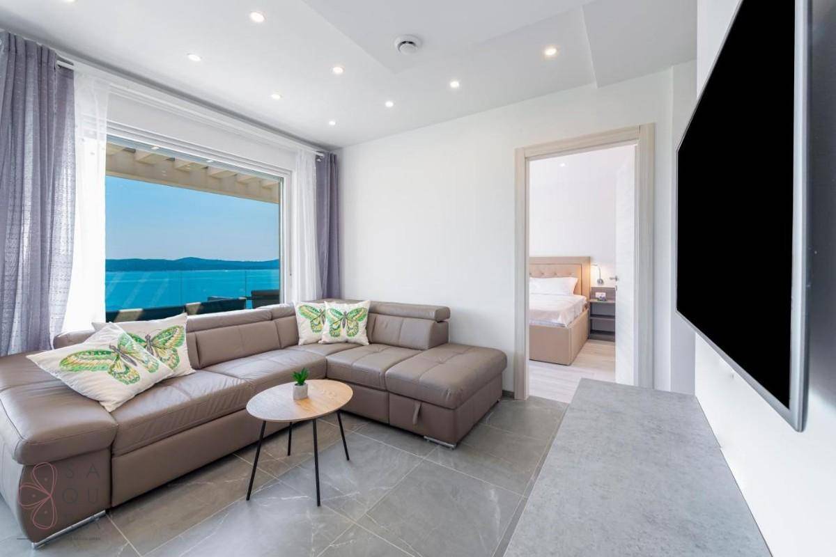 Modernes Wohnzimmer mit beigem Sofa und Zugang zu einem Schlafzimmer, bietet Meerblick.