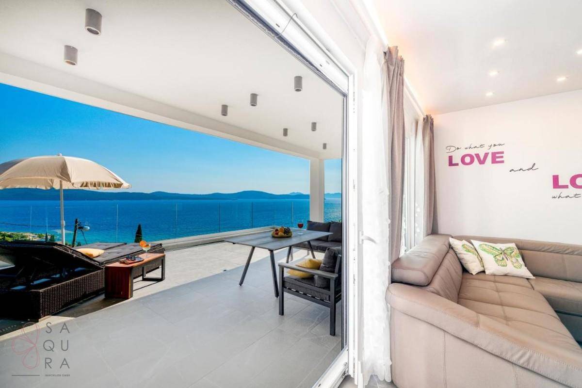 Gemütliches Wohnzimmer mit Sofa und direktem Zugang zur großen Terrasse mit Meerblick.