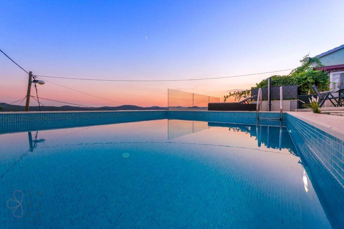 Ruhiger Poolbereich bei Sonnenuntergang mit Blick auf die umliegende Landschaft und das Meer.