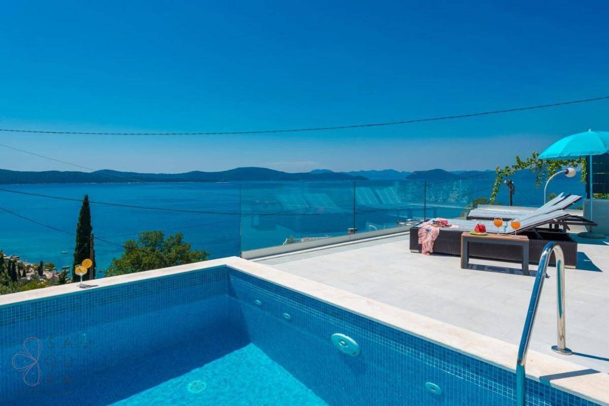 Infinity-Pool und Sonnenterrasse mit Liegen, bieten einen weiten Blick über das Meer.