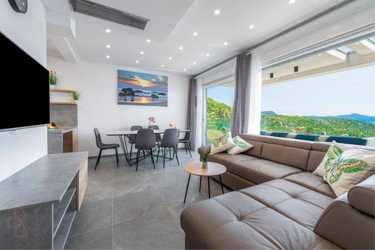 Heller Wohn-Essbereich mit beigem Sofa und Esstisch, bietet weiten Meerblick durch große Fenster.