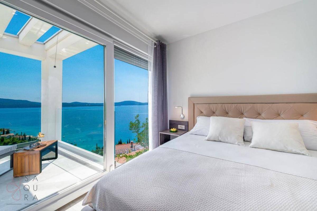 Helles Schlafzimmer mit Doppelbett und raumhohen Fenstern, bietet einen atemberaubenden Meerblick.