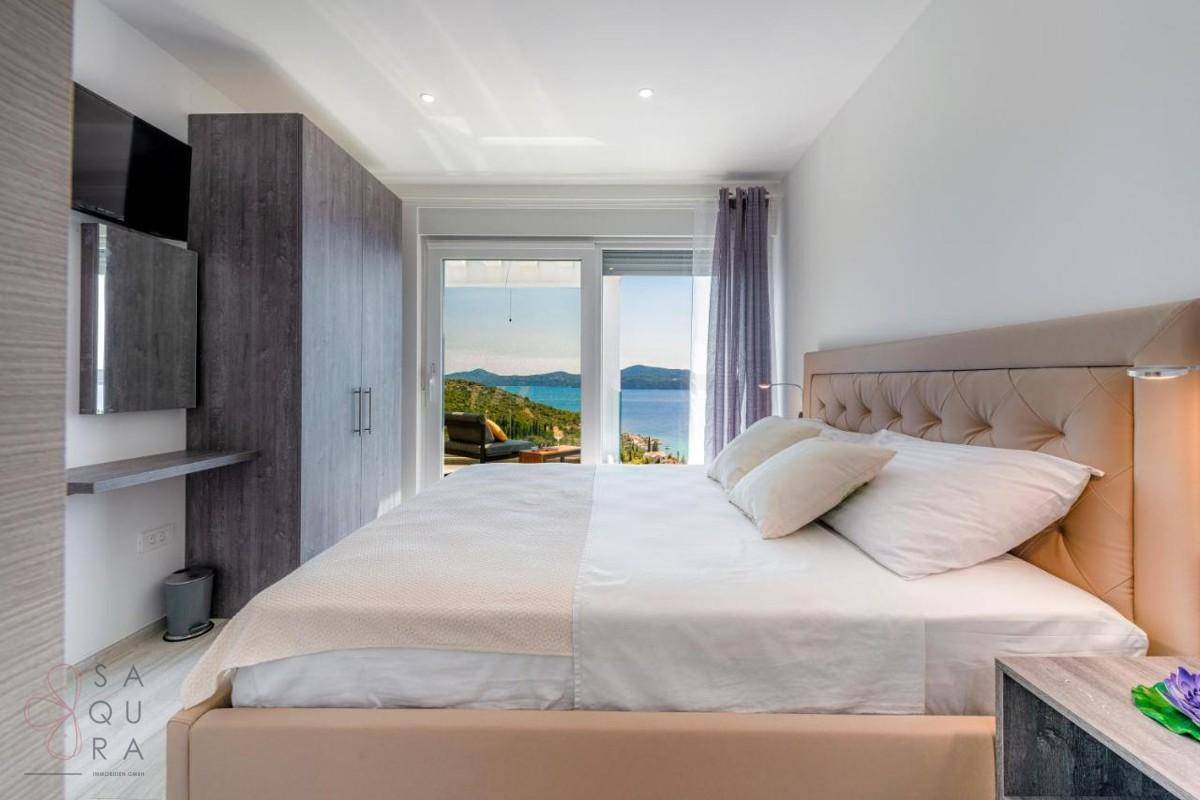 Helles Schlafzimmer mit Meerblick, Zugang zum Balkon und modernen Einbauschränken.