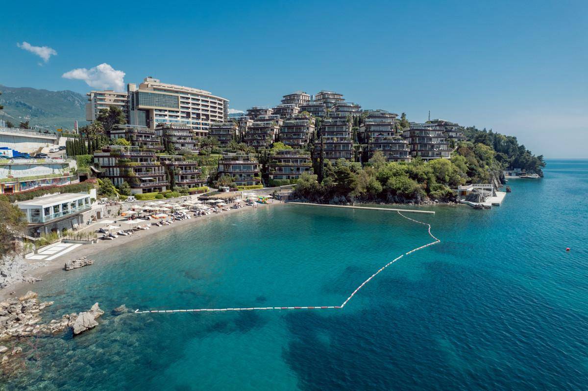 Panoramablick auf die luxuriöse Küstenanlage mit terrassierten Gebäuden und privatem Strandbereich.