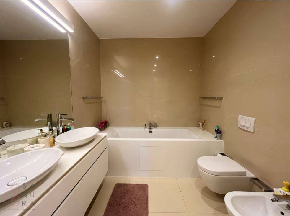 Geräumiges Badezimmer mit Badewanne, Doppelwaschbecken, Wand-WC und Bidet in modernem Design.