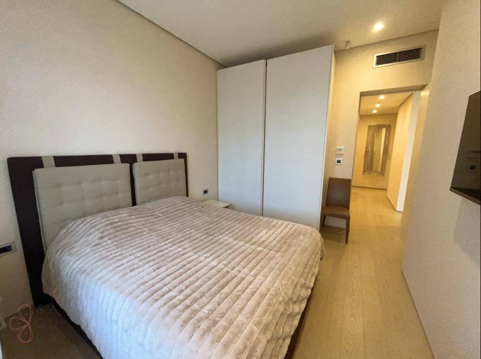 Modernes Schlafzimmer mit Einbauschränken, hellem Holzboden und Klimaanlage, führt zu einem Flur.