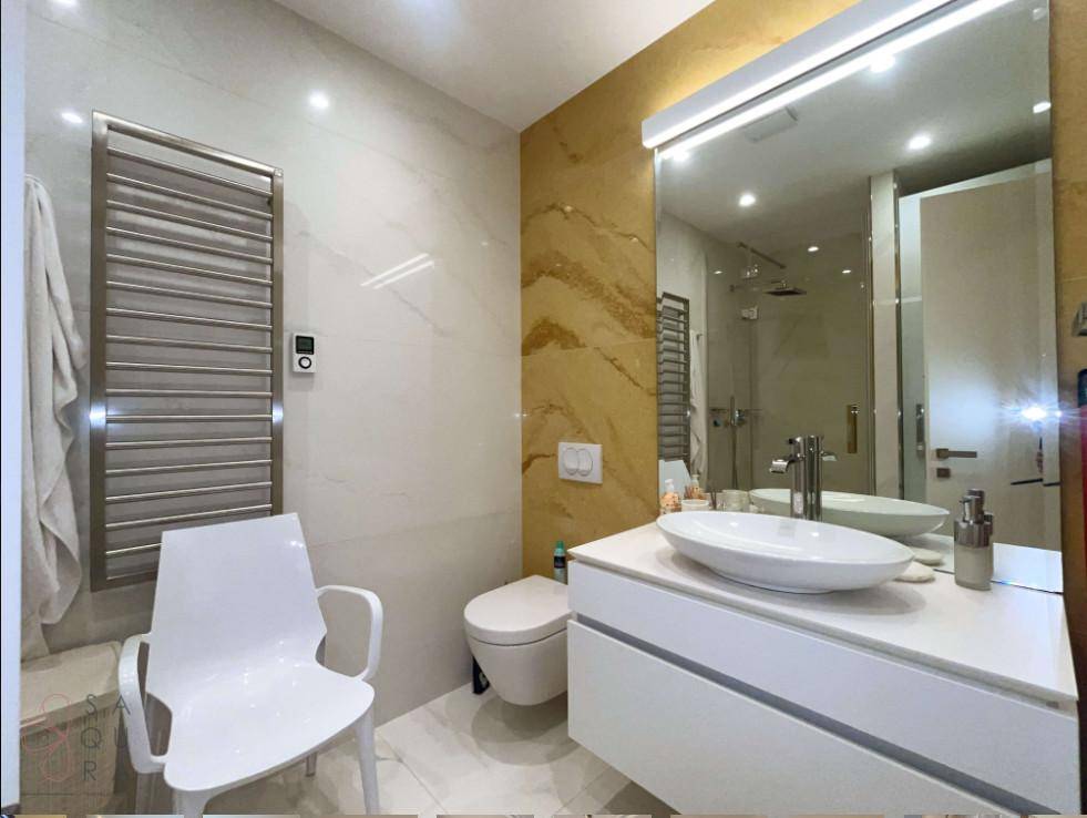 Stilvolles Badezimmer mit Einzelwaschbecken, Wand-WC und beheiztem Handtuchhalter, elegant gestaltet.
