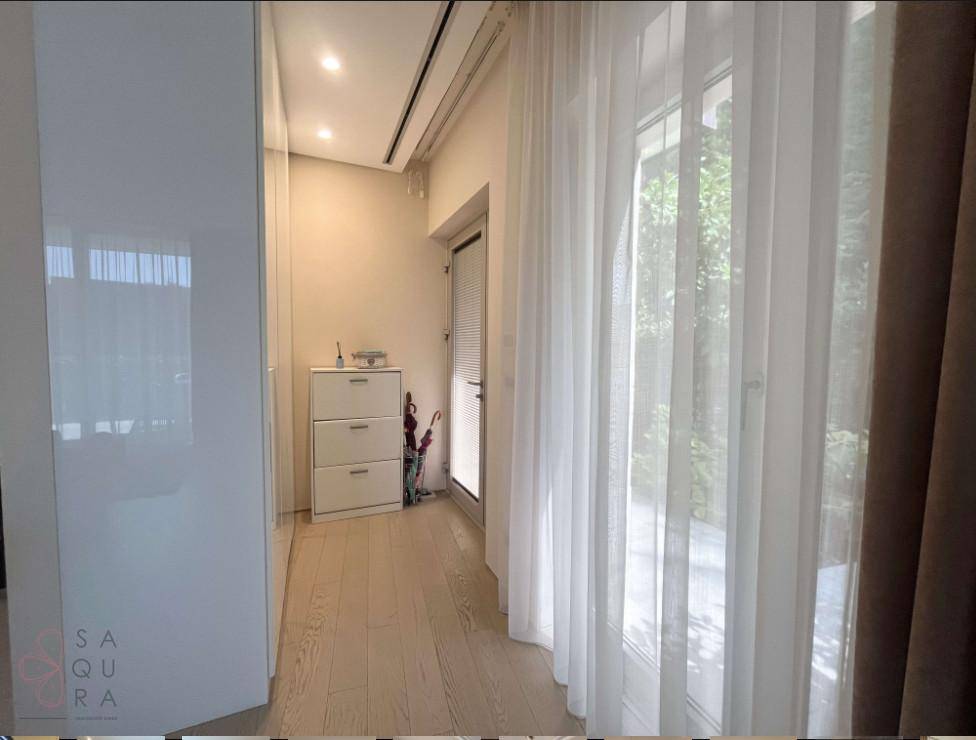 Heller Flur mit Einbauschrank, Holzboden und direktem Zugang zu einem sonnigen Balkon.