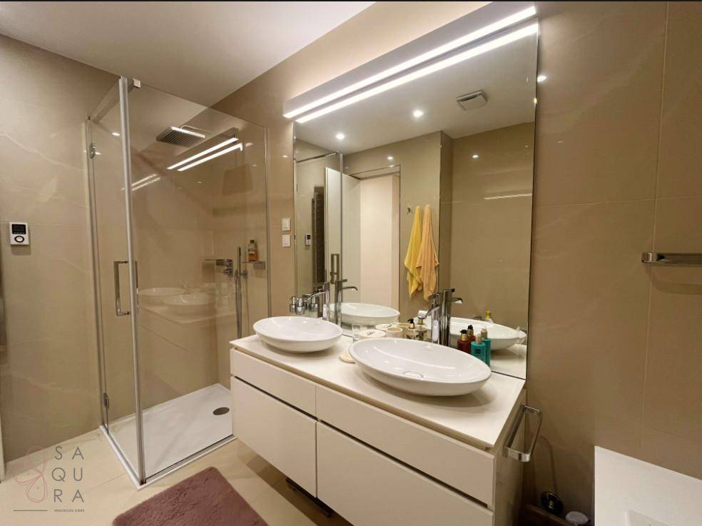 Elegantes Badezimmer mit Doppelwaschbecken, großer Duschkabine und Spiegelfläche, bietet viel Komfort.