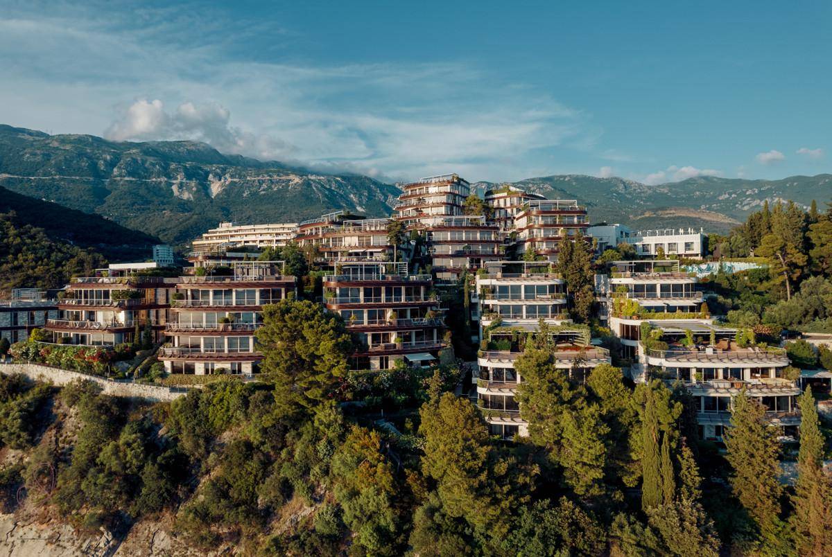 Beeindruckende Architektur der terrassierten Gebäude, eingebettet in die grüne Hügellandschaft mit Bergblick.
