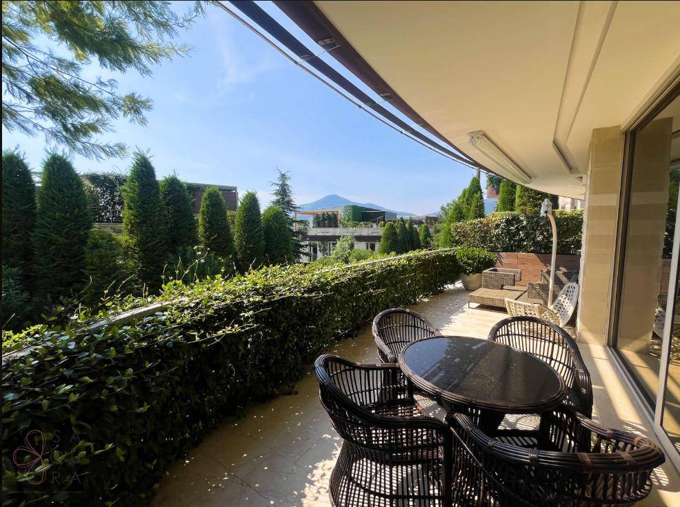 Sonniger Balkon mit Esstisch und Stühlen, umgeben von üppiger Vegetation, perfekt für Mahlzeiten im Freien.