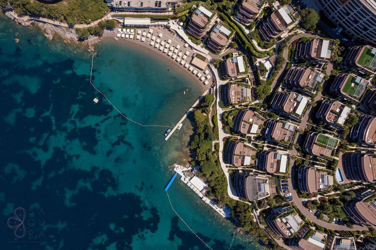 Luftaufnahme einer luxuriösen Küstenanlage mit Privatstrand und türkisblauem Meer.
