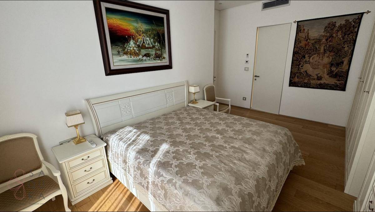 Elegantes Schlafzimmer mit Doppelbett, Nachttischen und Kunstwerken an den Wänden.