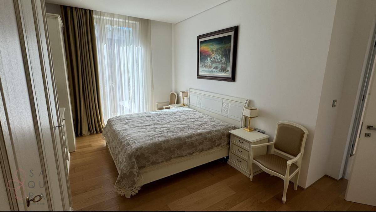 Helles Schlafzimmer mit Holzboden, großem Bett und Zugang zu einem Balkon oder Fensterbereich.