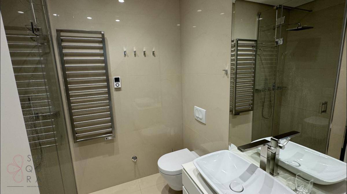 Modernes Badezimmer mit begehbarer Dusche, beheiztem Handtuchhalter und elegantem Einzelwaschbecken.